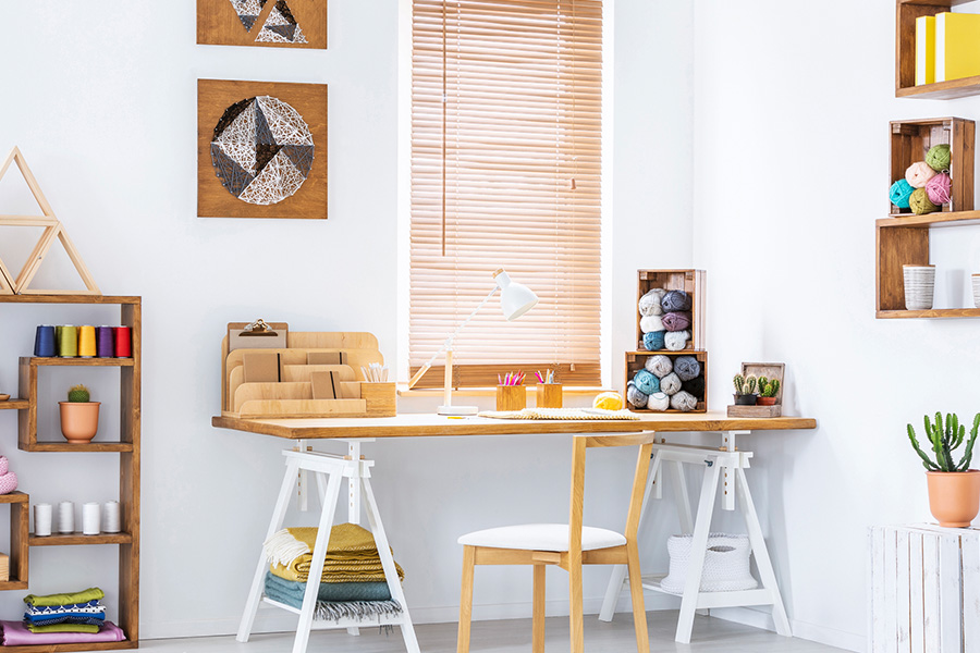 Light oak wood blinds add a natural element to your living space. Wood blinds in a white and airy craft corner.