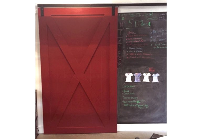 Bright red sliding barn door with black hardware next to chalkboard 🚪